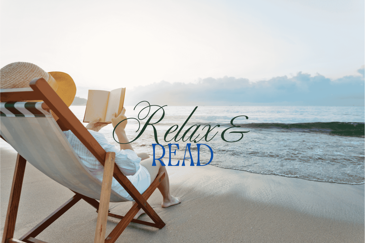 Woman in beach chair with sun hat reading a book by the water
