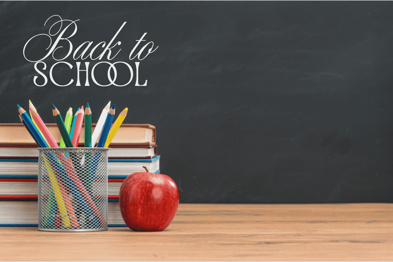 stack of books behind a full pencil jar and red apple