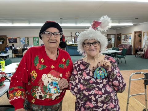 Tow friends display their winning Ugly Sweater designs.