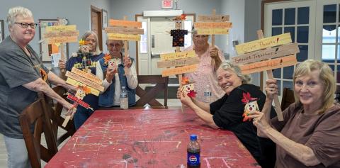 Friends display their Welcome yard sign crafts at Kenton Station Senior Villas.
