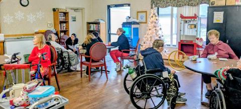 Residents of Kenton Nursing and Rehab sit at tables working on crafts in their activity room.