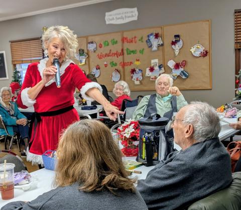 Melissa Tewers sings Santa Baby and teas Glenn at Hardin County Council on Aging while others smile and enjoy the performance.